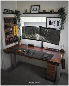 a computer desk with two monitors on top of it next to a shelf filled with pictures