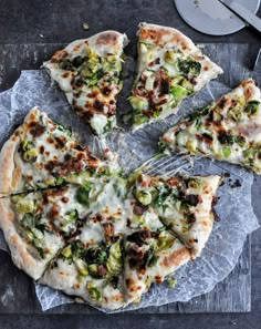 a pizza with broccoli, cheese and other toppings on it next to a spatula