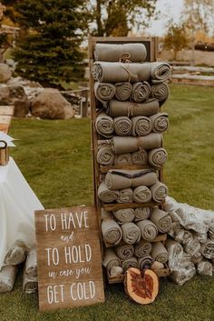 a stack of folded towels sitting next to a wooden sign that says to have and to hold in case you get cold