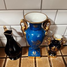 three vases sitting on top of a tile floor next to each other in front of a white tiled wall