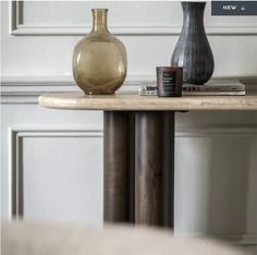 two vases sitting on top of a wooden table next to a book and magazines