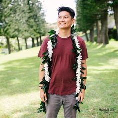 a man standing in the grass with a lei around his neck