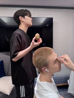 a young man is getting his hair cut by another person in front of the mirror