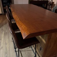 a wooden counter top sitting on top of a hard wood floor next to two brown barstools