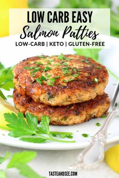 two salmon patties on a plate with lemon wedges and parsley garnish