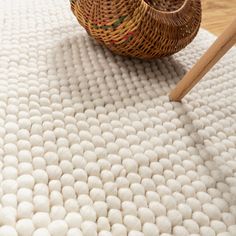 a basket sitting on top of a white rug next to a wooden flooring brush