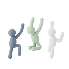 three small plastic figurines in different colors and sizes, one holding up the other's hand