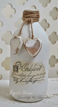 a white bottle with two hearts hanging from it's side and some twine