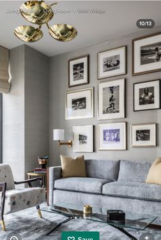 a living room filled with furniture and framed pictures on the wall above a glass coffee table