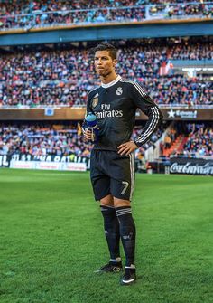 a man standing on top of a soccer field in front of a stadium filled with people