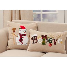 two christmas pillows sitting on top of a couch