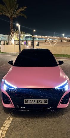 a pink and blue car parked in front of a palm tree