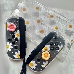 two nintendo wii controllers sitting next to each other on top of a white table with yellow and pink buttons