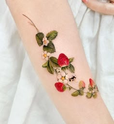 a woman's arm with flowers and strawberries on it