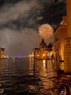 fireworks are lit up in the night sky over water and buildings on both sides of the river