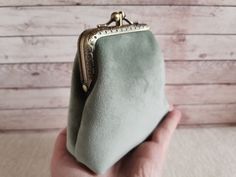 a hand holding a small green purse on top of a table