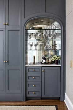 a kitchen with gray cabinets and glass shelves