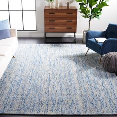 a blue and white rug in a living room next to a couch with a plant on it