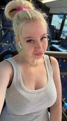 a woman sitting on a bus with her hair in a bun and wearing a tank top