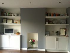 a living room filled with furniture and bookshelves next to a fire place on top of a hard wood floor