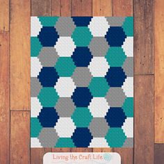 a blue and gray quilt hanging on a wooden wall next to a sign that says living the craft life