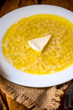 a white bowl filled with soup and a piece of cheese on the top of it