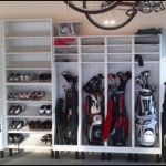 an organized closet with lots of shoes and golf gear on shelves in front of a chandelier