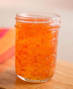 a jar filled with orange liquid sitting on top of a wooden table