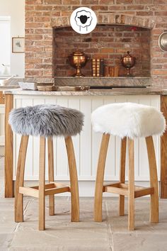 two stools in front of an oven with a brick wall and countertop behind them