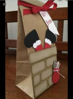 a brown paper bag with stockings and mittens on it sitting on a wooden table