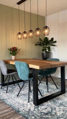 a dining room table with blue chairs and hanging lights