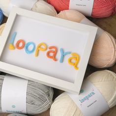 the word lora spelled with yarn in front of balls of yarn and crochet