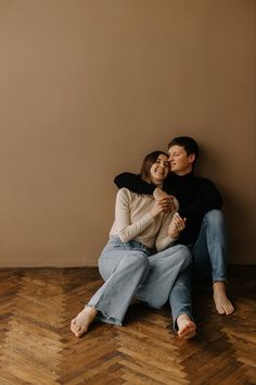 a man and woman are sitting on the floor hugging each other with their eyes closed