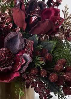 a vase filled with red flowers and greenery