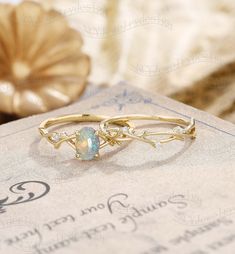 an opal ring sits on top of a book next to a gold plated object