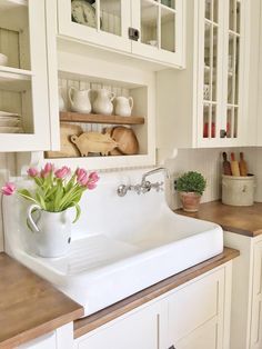 a white sink sitting under a window next to a wooden counter top in a kitchen