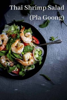 shrimp salad with lettuce and tomatoes in a black bowl on top of a table