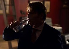 a man in a suit drinking from a water bottle