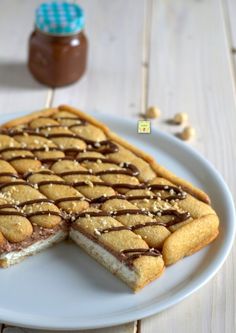 a white plate topped with two pieces of cake next to a jar of peanut butter