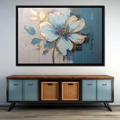 a painting hanging on the wall above a blue cabinet with two baskets underneath it and a large flower