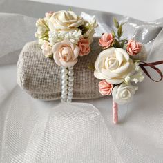 two small bouquets with flowers on top of a white cloth covered bag, one is tied to a string and the other is wrapped in burlock