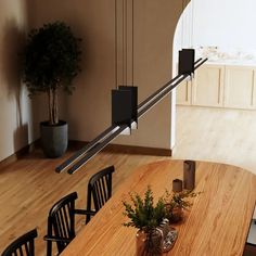 a wooden table topped with black chairs next to a plant on top of a hard wood floor