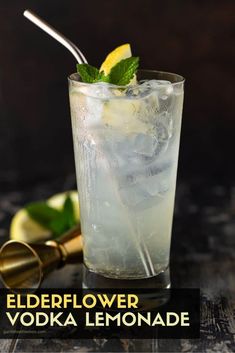 a tall glass filled with ice, lemon and mint on top of a wooden table