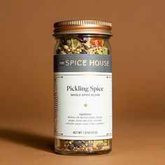 a jar filled with pickling spice sitting on top of a brown table next to a wall