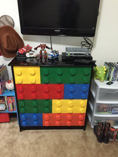 a flat screen tv sitting on top of a colorful lego chest in front of a television