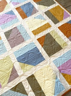 a multicolored quilt is laying on the floor