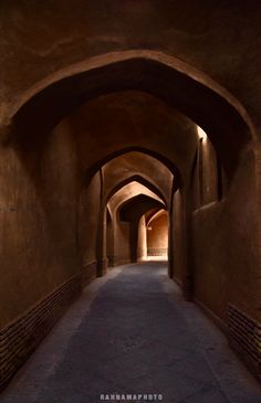 an archway leading into a tunnel with light at the end and brick walls on both sides