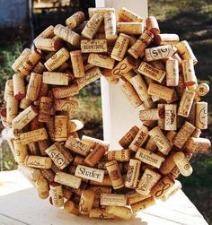 a wreath made out of wine corks sitting on top of a white fence post