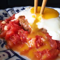 a plate topped with meat and vegetables covered in gravy next to an egg