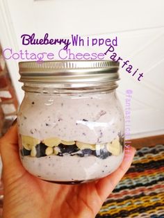 a hand holding a mason jar filled with blueberry whipped cottage cheesecake art